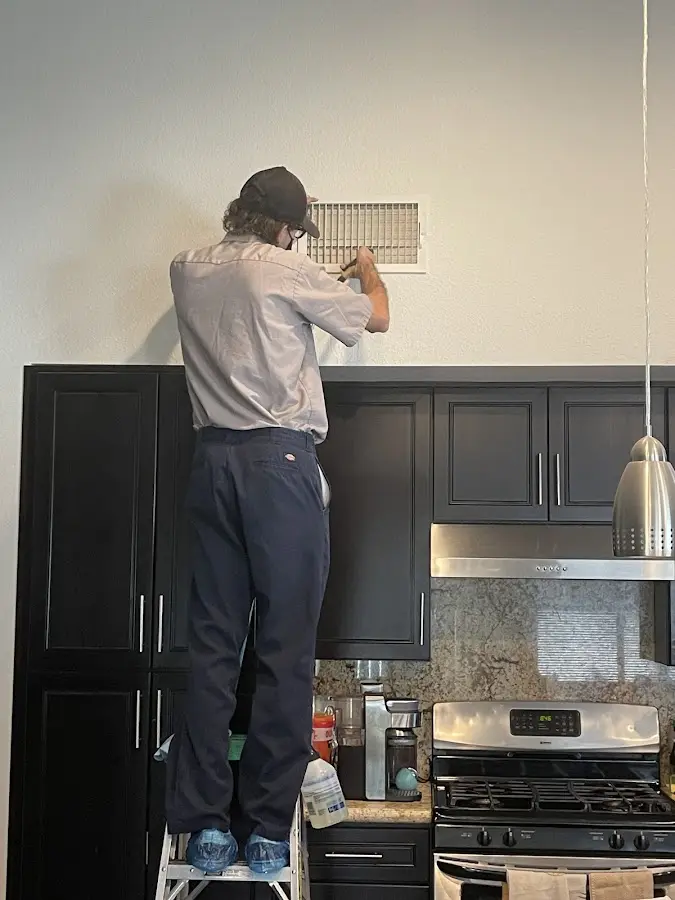 Technician inspecting an air vent during HVAC service in Four Corners